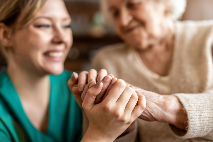 Nurse clasping senior hand of senior woman